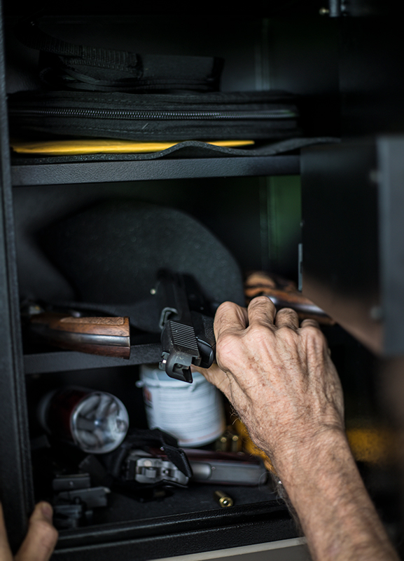 Close up of Older Man placing hand gun inside Small Gun Safe